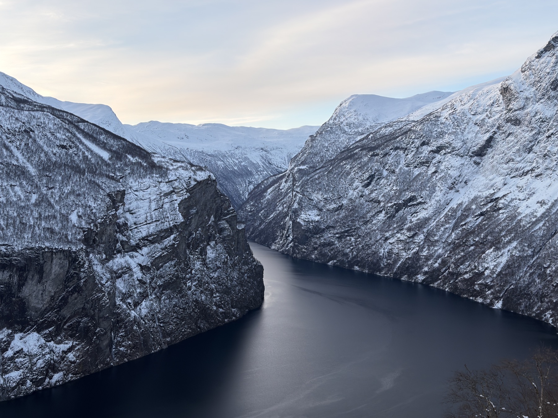 A Norwegian fjord framed by steep snow-covered mountains and dark water